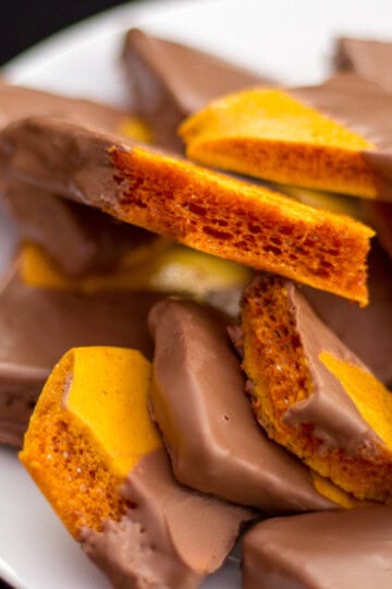 Chocolate cinder toffee pieces on a white plate.