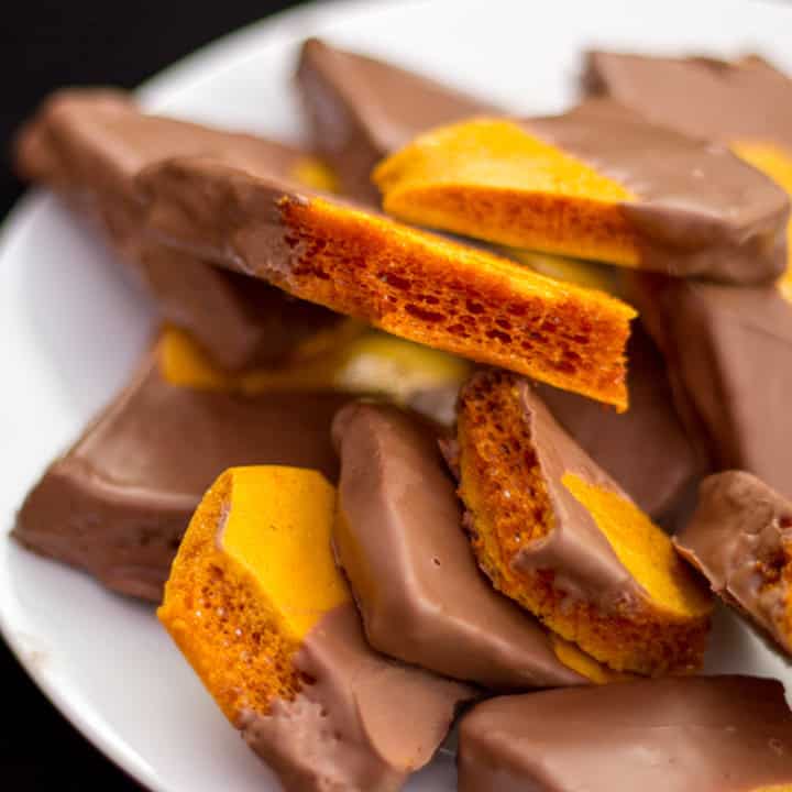 Chocolate cinder toffee pieces on a white plate.
