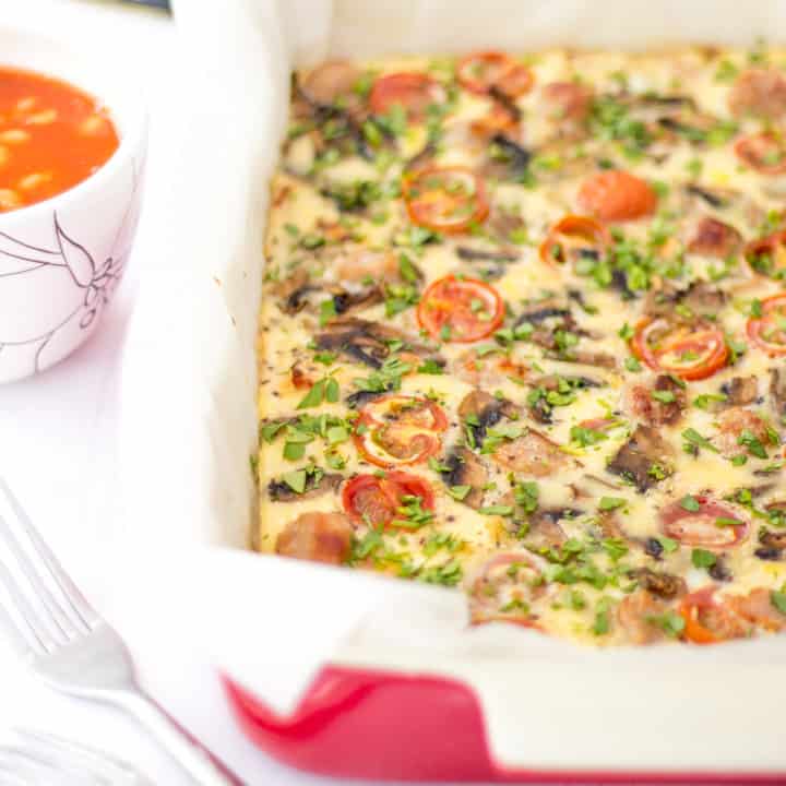 A large oven proof dish with a full English frittata inside, and a pot of beans at the side.