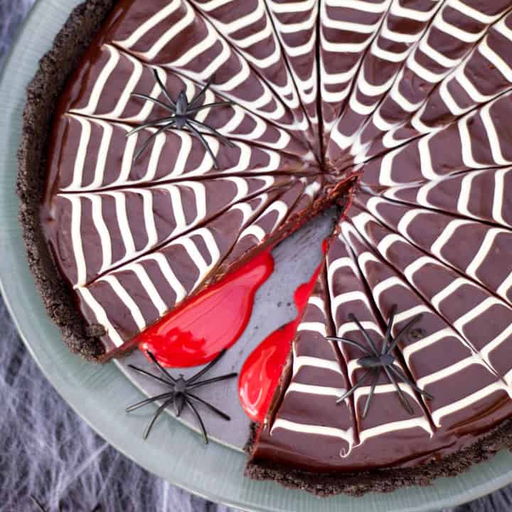 A chocolate tart decorated with a white chocolate spiderweb on top, and filled with caramel blood.